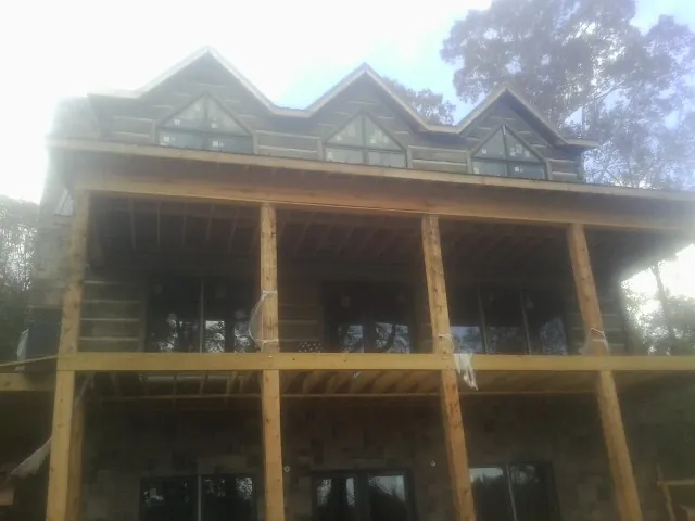 Dormers and porch framing on a large log home under construction — Roof Coating work by our crew in Rushmore