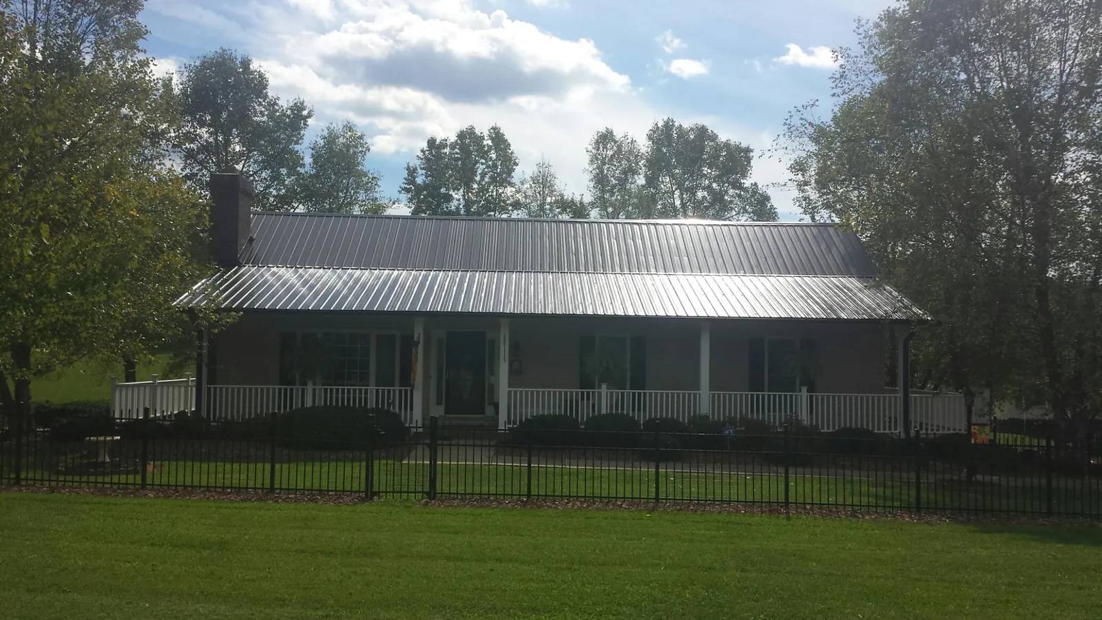 Gray metal roof on a brick ranch with a full width front porch — Gutter Guard Installation work by our crew in Rushmore