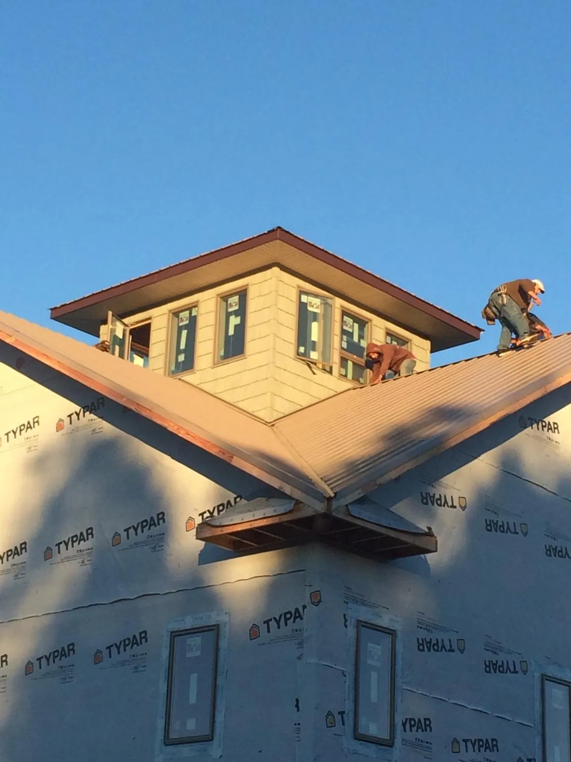 Roofers working around a rooftop cupola on a new metal roof at sunset — Roof Waterproofing in Rushmore by Roofing Brothers